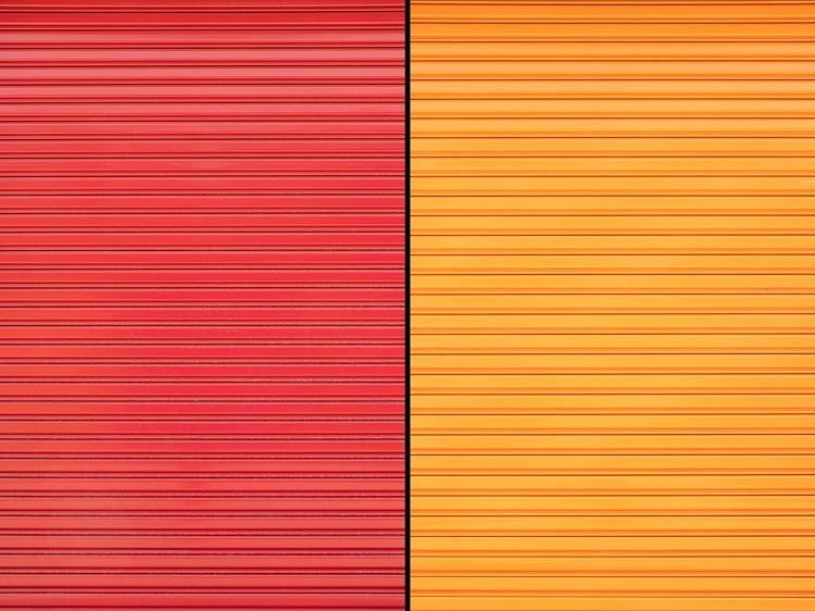 Two adjacent metal garage doors in solid orange and red