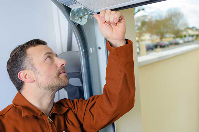 Man in orange dress shirt inspecting parts of open garage door