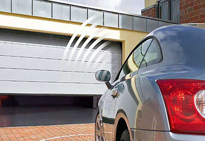 Parked car in driveway and animation of garage door remote signal facing partially open garage door