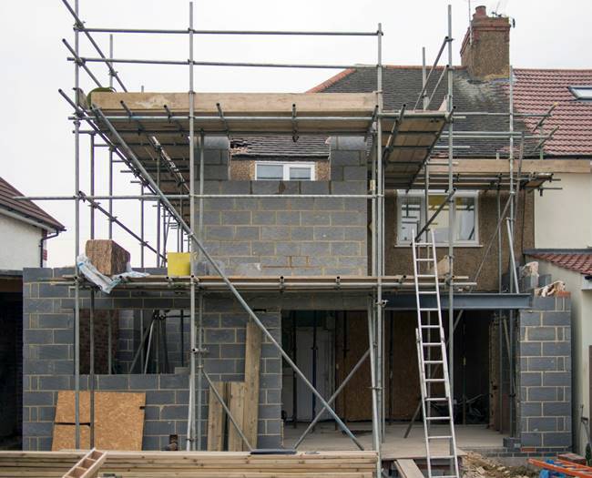 Partially-constructed brick garage and adjacent ladder