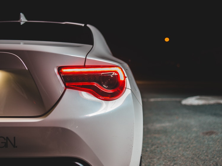 White sedan backing into residential driveway at night