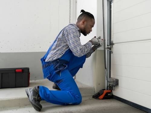 Garage door technician lubricating vertical tracks
