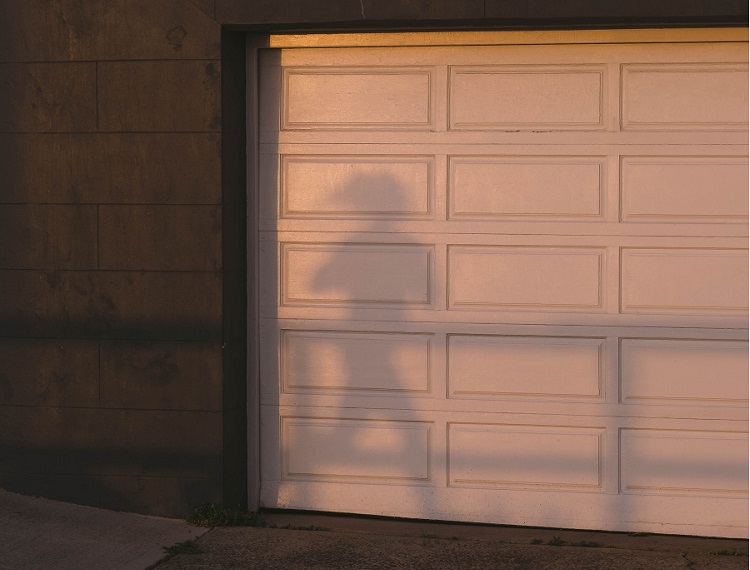Residential garage with gray slate siding and white wooden paneled garage door
