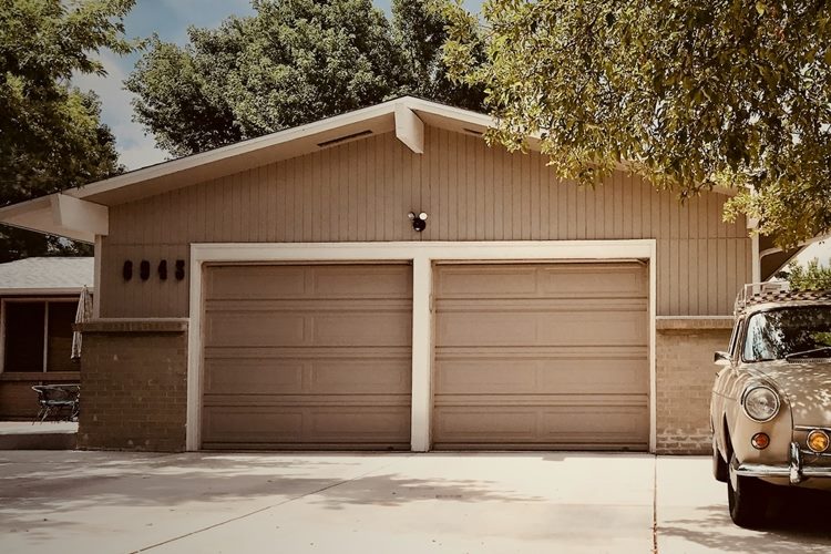 Tan-colored one-story home with two-car garage and white trim