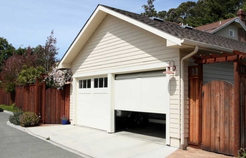 Paneled white residential garage door stuck halfway open