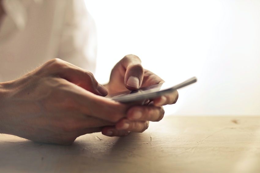Woman at Kitchen Table Selecting Garage Door App on Smartphone
