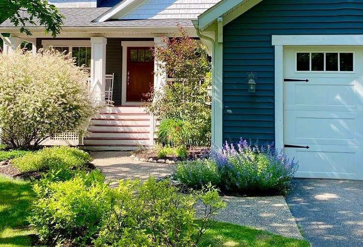 Blue suburban home with white garage door with windows and accents