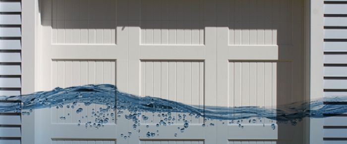 While paneled garage door and adjacent floodwater in driveway