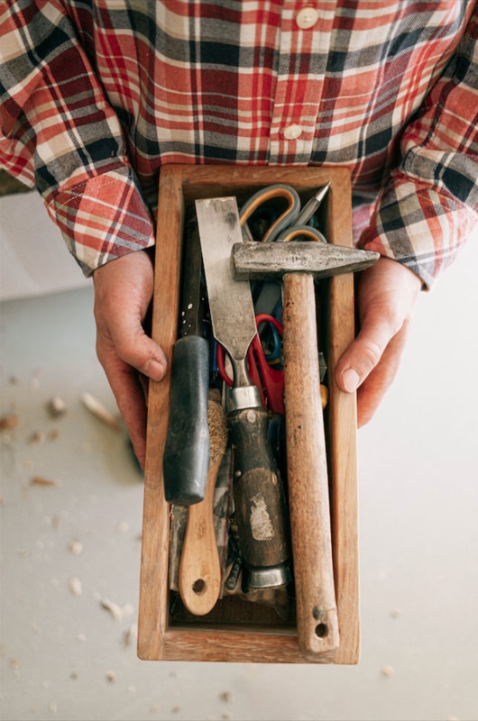 Homeowner in flannel shirt holding toolbox with hammer, wrench and other tools for DIY repair work
