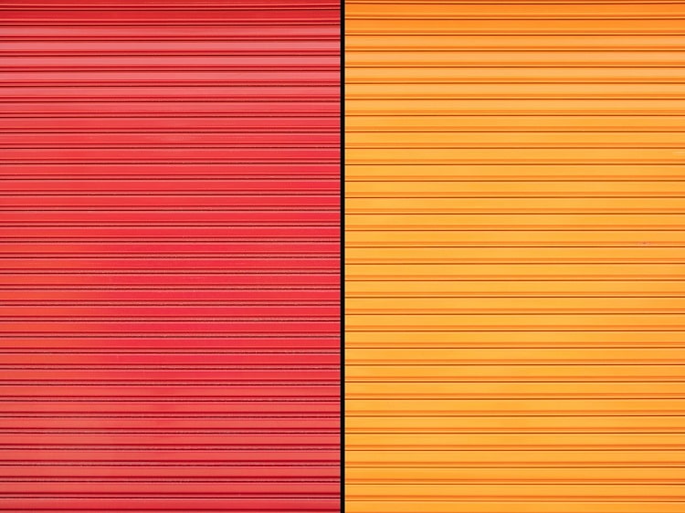 Two adjacent metal garage doors in solid orange and red
