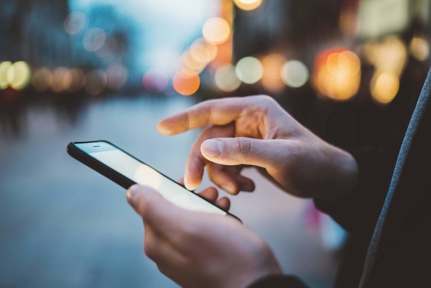 Hand of user scrolling android smartphone in city at dusk