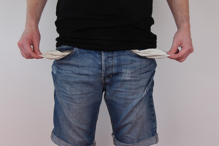 Man in black T-shirt and jeans holding fabric of empty front pockets