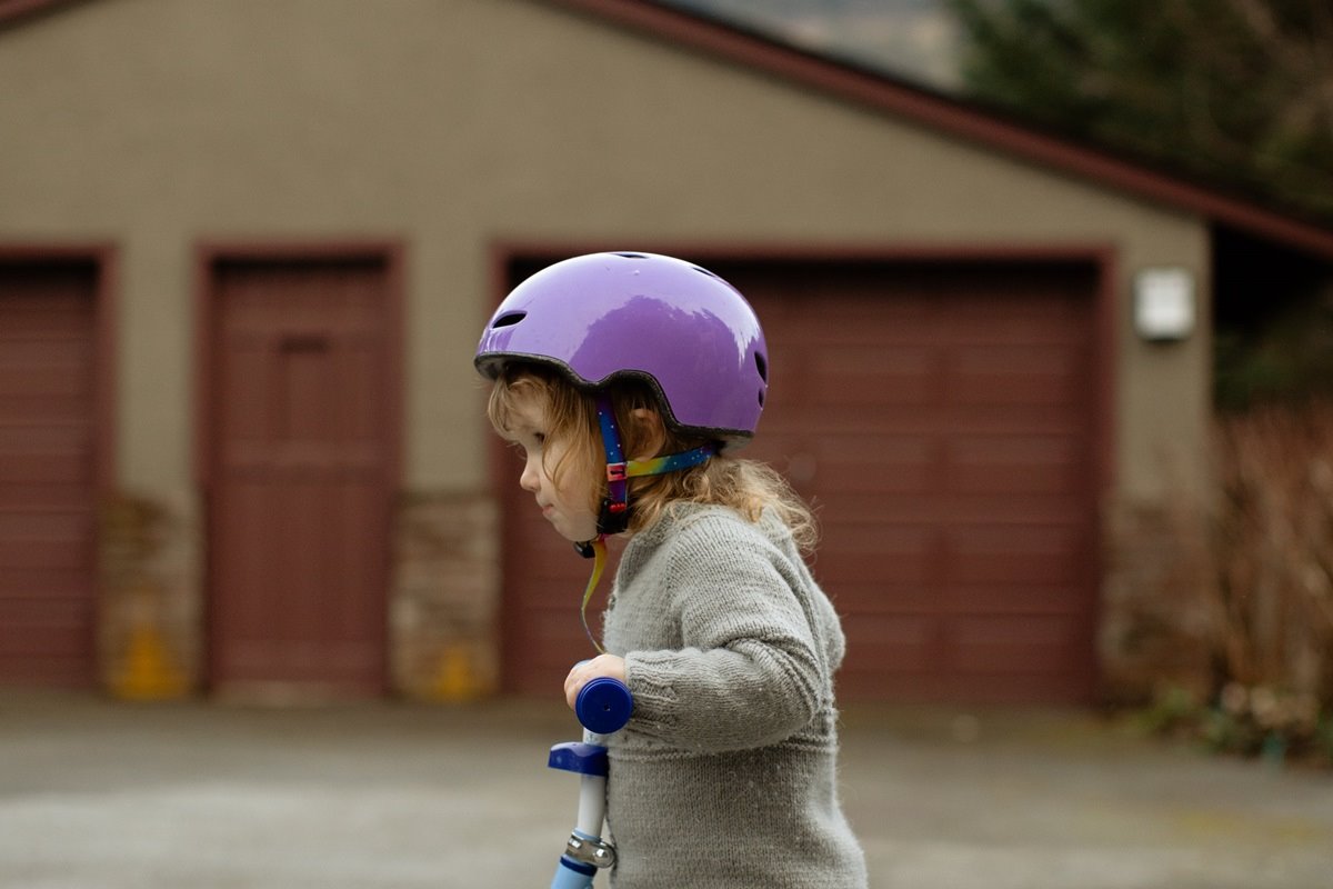 Young child on tricyle in driveway in front of garage door