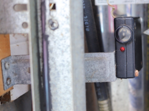 Dirty photocell beside vertical tracks of residential garage door