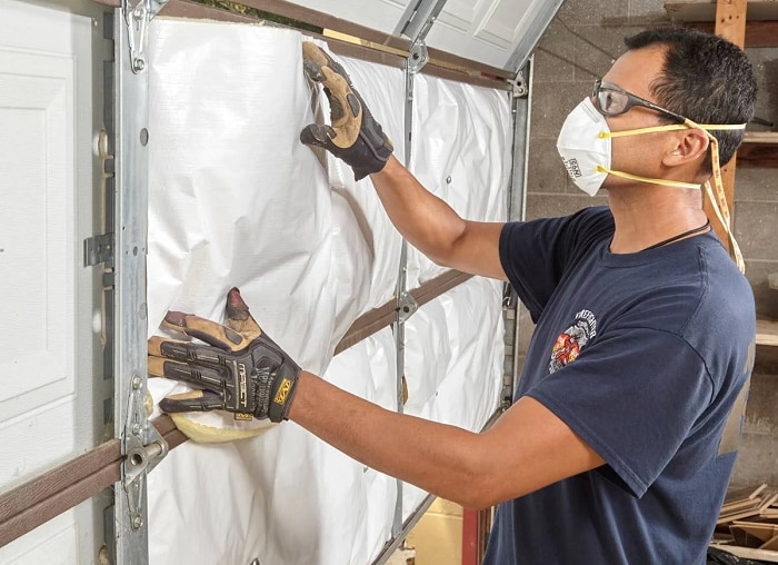 Garage door installer adding insulation to new garage door's interior surface