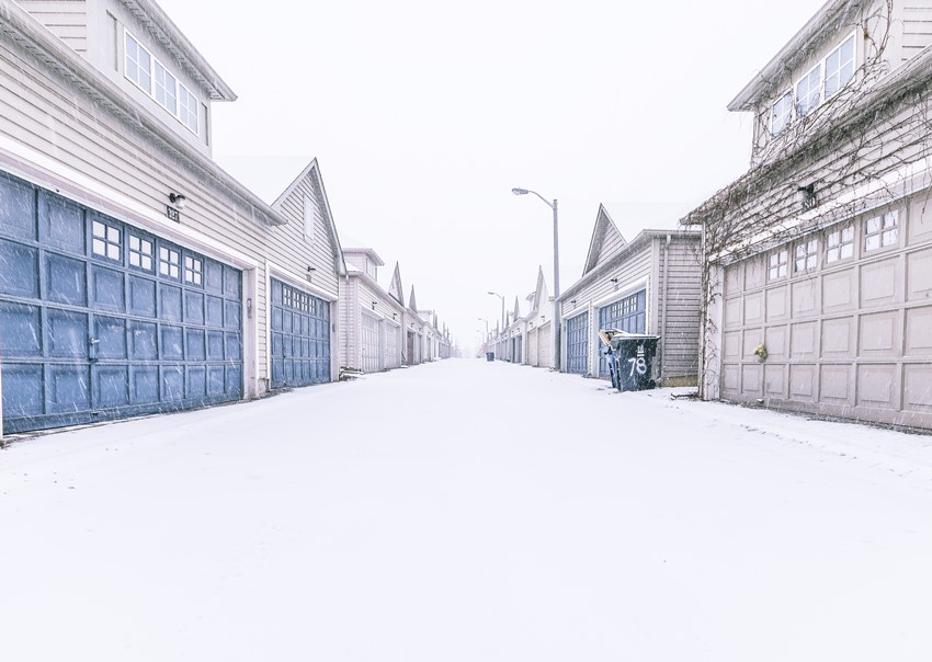Garages of suburban homes lining snowy residential street