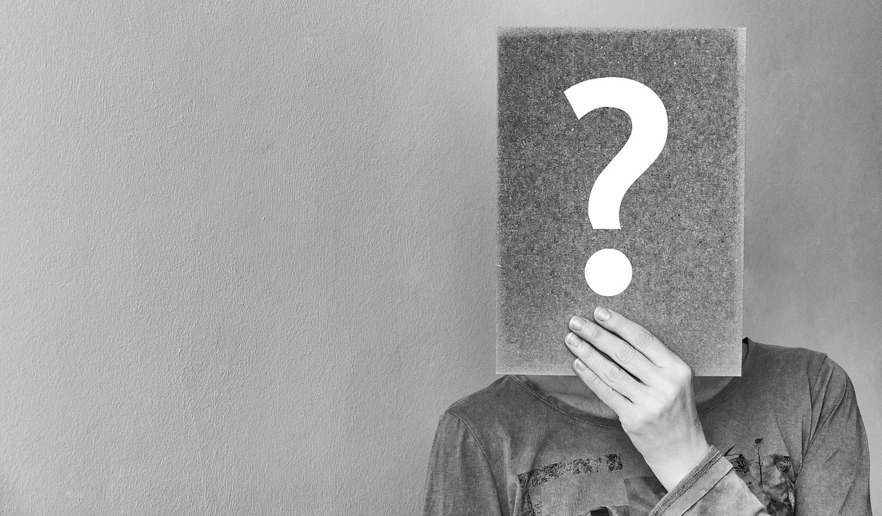 Black and white image of a man hiding his face behind a question mark sign, showing confusion about his garage door issue