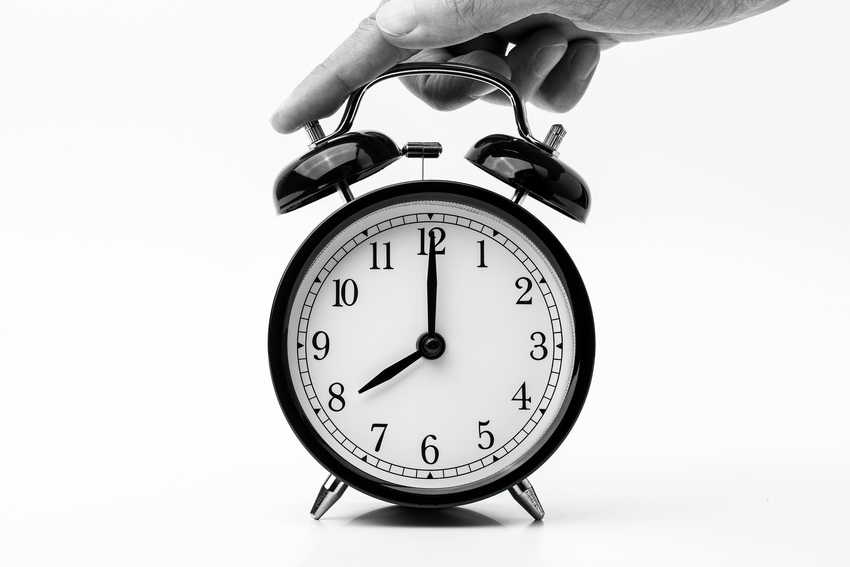 Ringing Analog Alarm Clock Against White Surface With Hand Pressing Top to Turn Off