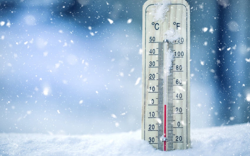 Thermometer wedged into snowbank as surrounding snowflakes fall
