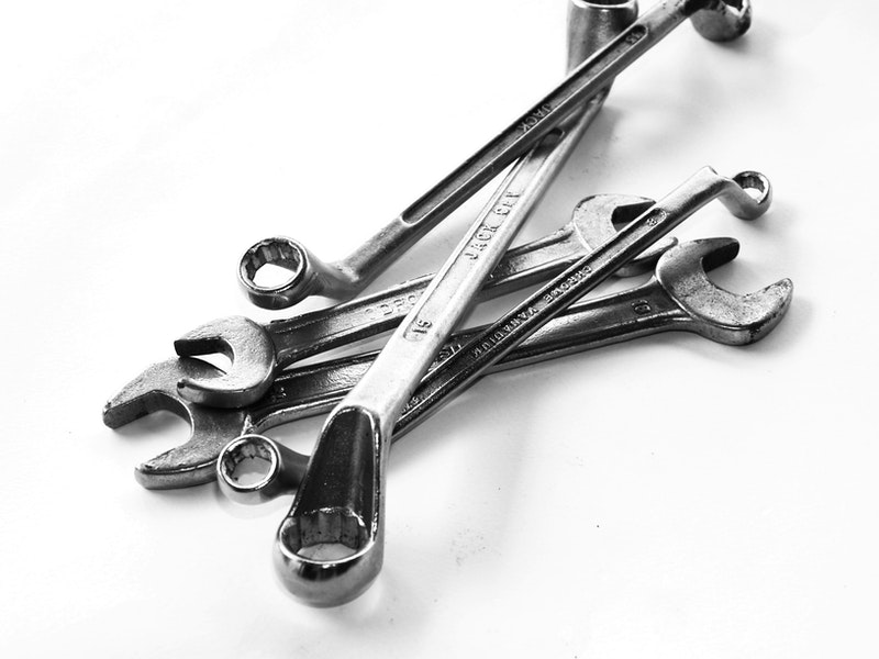 Wrenches of assorted sizes stacked on flat, white surface