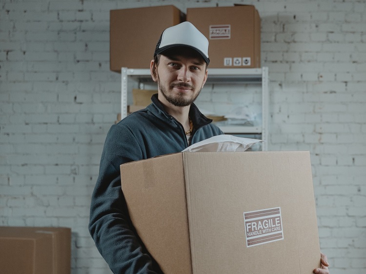 Smiling man standing in garage holding cardboard storage box