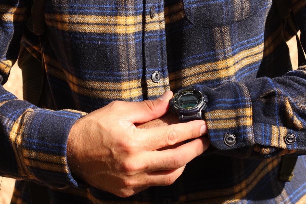 Man in flannel shirt checking digital wristwatch