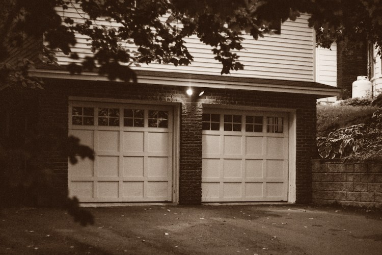 Sepia photograph of two-car garage with white paneled doors and windows