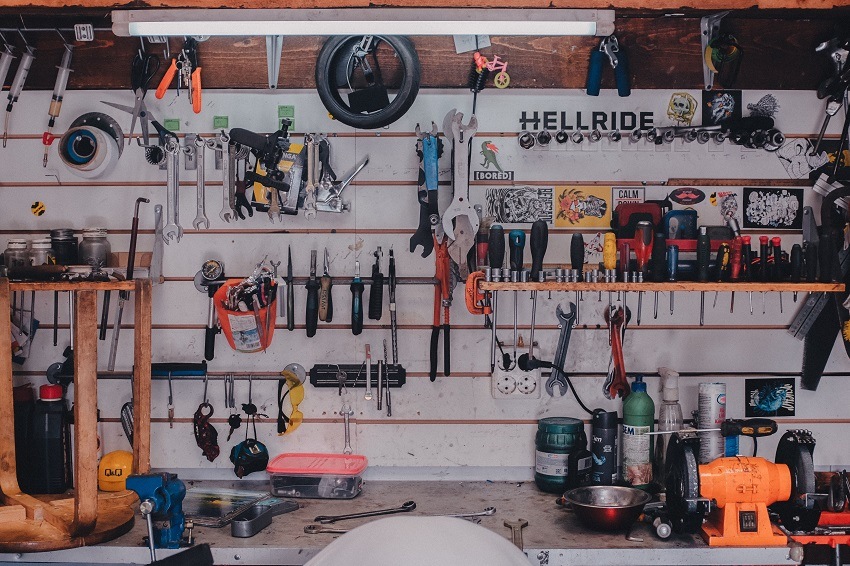 Wrenches, screwdrivers, pliers and other repair tools on wall and shelf of garage workshop
