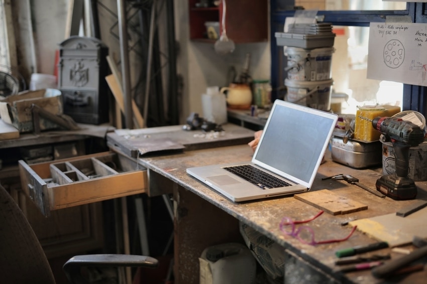 Messy workspace of homeowner preparing for do-it-yourself garage door repair with laptop on desk, tools and open drawers