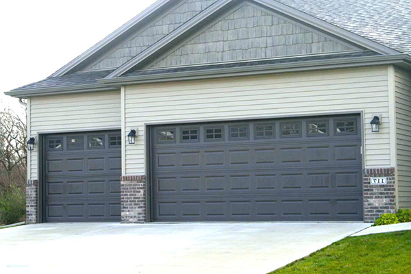Black, paneled two-car garage door on suburban home with brick exterior