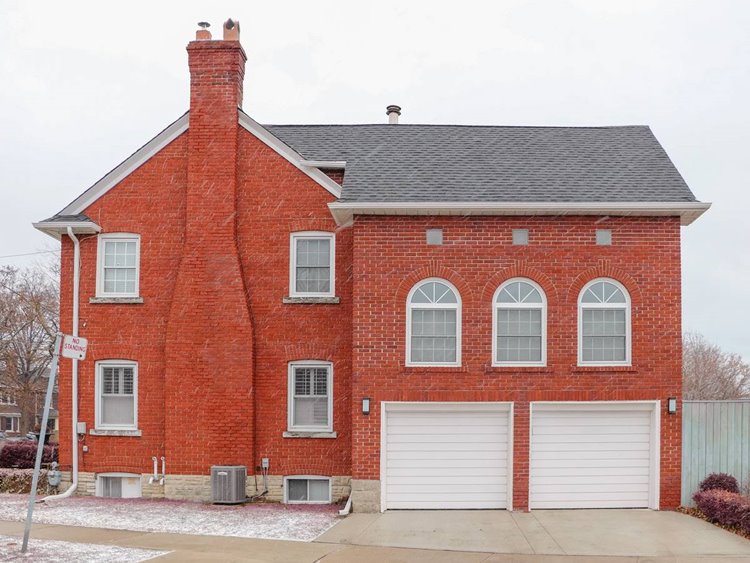 Two-story red brick residential home with two-car white paneled garage door on gray, winter day