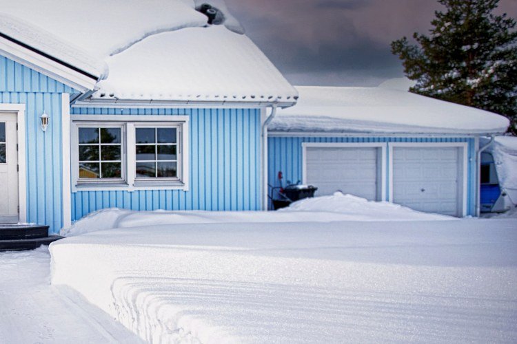 Blue house with two-car garage surrounded by snow
