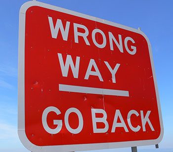 Red road sign reading 'WRONG WAY - GO BACK'