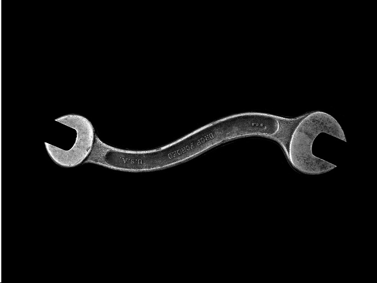Bent silver wrench against black background