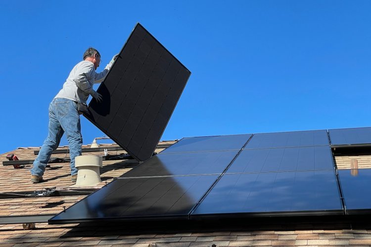 Technician installing solar panels on residential rooftop