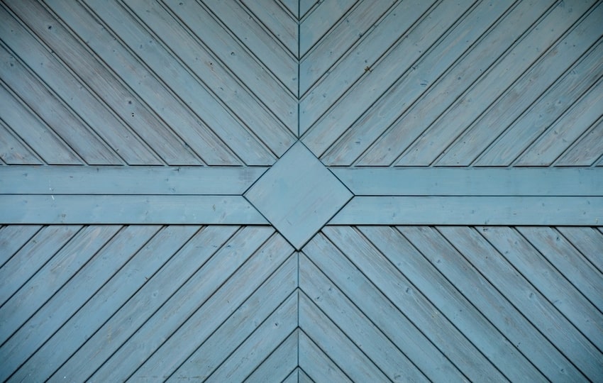 Close-up view of unique, custom-designed blue wooden garage door with diagonal slats after Broomfield, CO installation