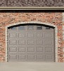 Brown paneled garage door with windows on garage with brick exterior